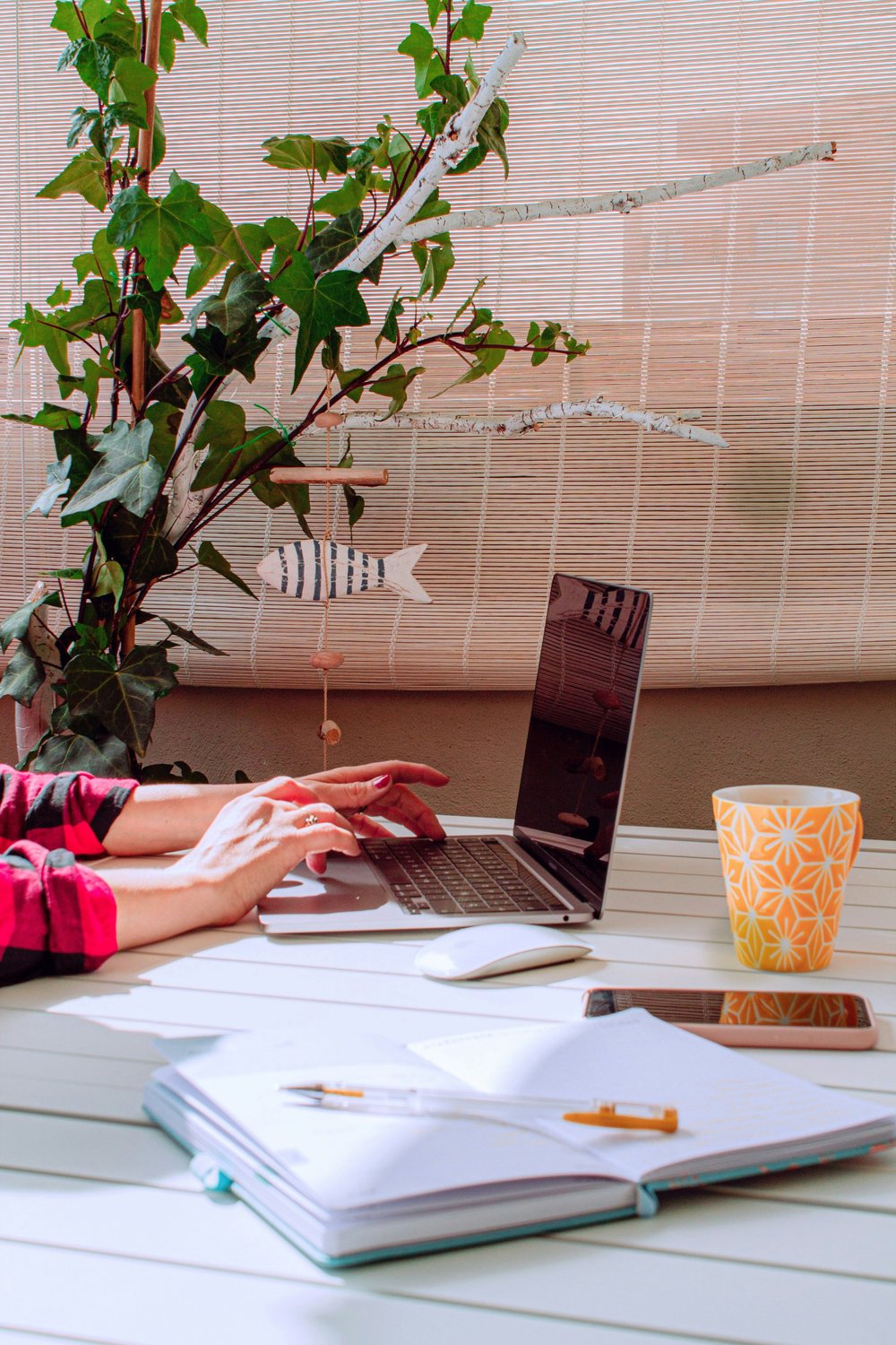A person working on a laptop at a bright home workspace